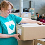 Treasure Boxes volunteer in a teal t-shirt picking up a linen box